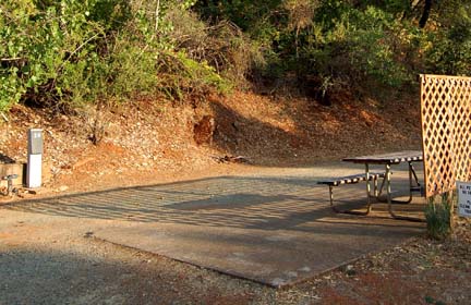 A level back-in site with picnic table and hook-up post in evening light